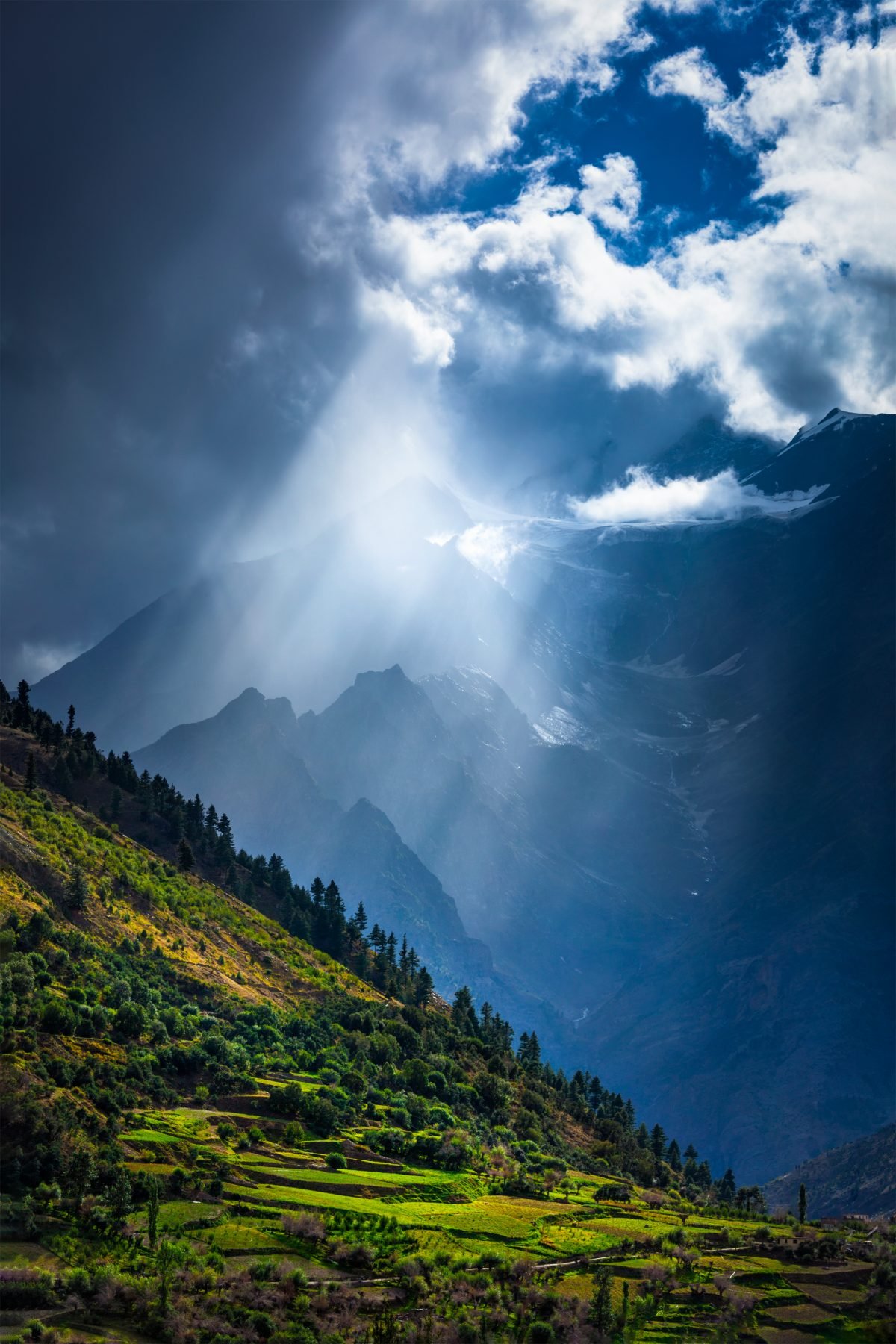 Sun rays through clouds over a Himalayan valley